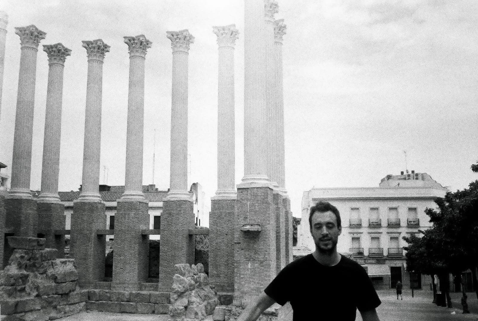 El mendigo digital, en blanco y negro, delante de unas columnas romanas